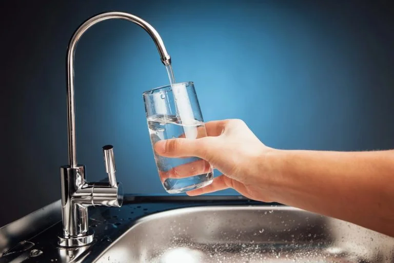 person using water filter to fill glass of water